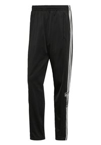 Black Adidas track pants with three white stripes running down the sides and zippered pockets on both hips.