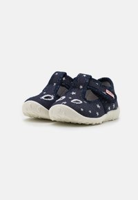 Navy modré látkové boty se vzorem bílých hvězd, elastickými pásky a texturovanou smetanovou gumovou podrážkou. Zaoblená špička a flexibilní design.