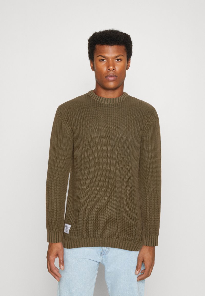 Grüner gestrickter Pullover mit Rippdesign, Rundhalsausschnitt, langen Ärmeln und seitlichen Schlitzen. Etikett sichtbar am linken Saum.