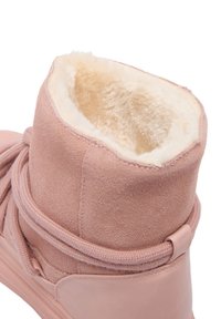 Růžová semišová kotníková bota s měkkou, krémovou umělou kožešinou uvnitř, zaoblený tvar a dekorační šněrování kolem kotníku.