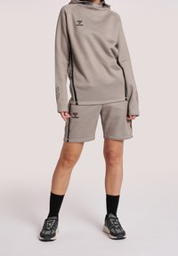 Conjunto deportivo de color gris claro que incluye una sudadera con capucha y pantalones cortos, confeccionado en una tela suave con detalles y logos en negro, diseñado para el uso activo.