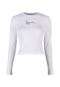 Hvit langermet cropped topp laget av ribbestrikket stoff med en svart signaturlogo på brystet. Rund hals og slim fit-design.