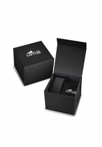 Schwarze Geschenkkartonage mit Deckel, auf dem oben ein weißes "LOTUS"-Logo prangt. Im Inneren befindet sich ein schwarzes Samtpolster zur sicheren Platzierung von Gegenständen.