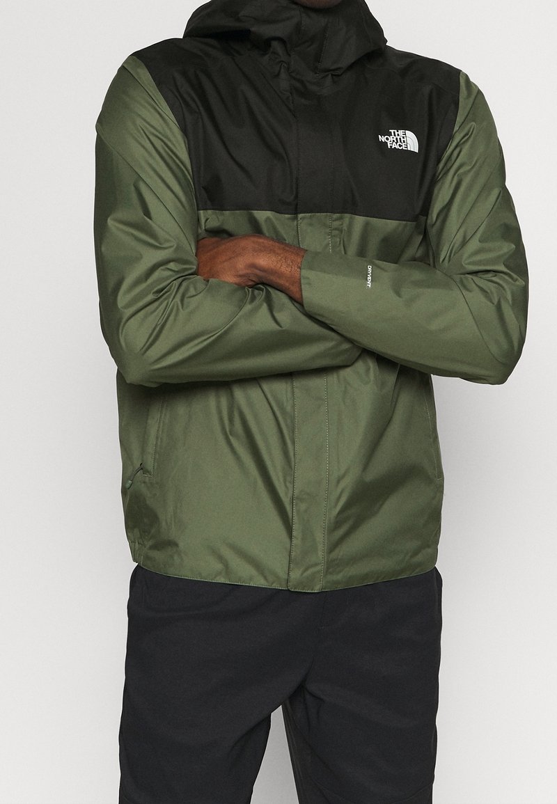 Veste North Face verte et noire avec capuche, dotée d'une fermeture éclair à l'avant, de longues manches, d'une texture lisse et d'un logo sur la poitrine.