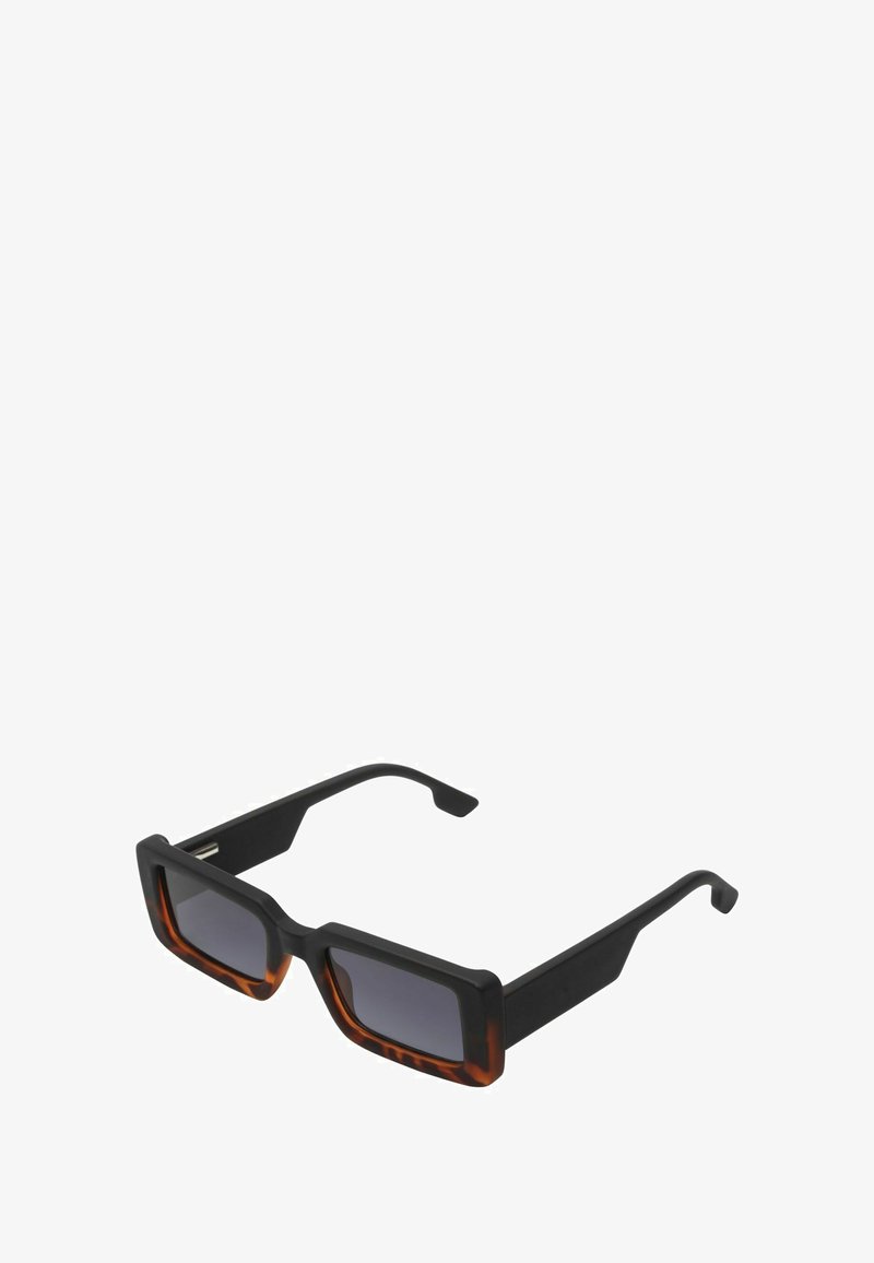 Lunettes de soleil avec une monture carrée présentant un motif noir et écaille de tortue. Verres sombres avec une finition mate sur la monture et des branches élégantes.