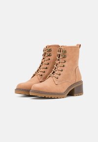 Bottines couleur tan en cuir lisse, dotées d'un lacet, d'œillets en métal et d'un talon bloc texturé avec une semelle en caoutchouc.