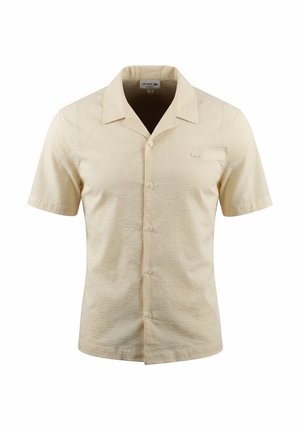 Beige short-sleeve button-up shirt with pointed collar and subtle textured fabric, unisex style, displayed against white background.