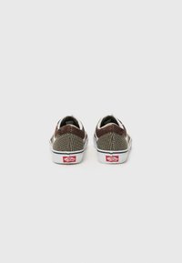Scarpe slip-on Vans con tomaia in rete nei toni della terra, suole in gomma bianca e dettagli del logo rosso sul tallone. Design con retro arrotondato.