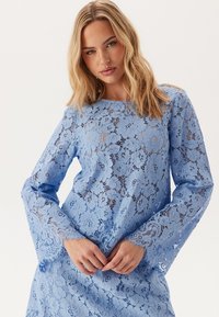 Abito in pizzo azzurro chiaro con maniche a campana lunghe e motivi floreali. Tessuto testurizzato con dettagli intricati e un aspetto leggermente trasparente.