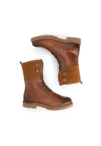 Bruine leren veterschoenen met suède bovenstukken en robuuste rubberen zolen, één schoen rechtop en de andere op zijn zij.