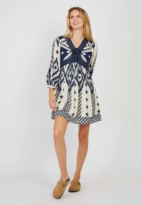 Navy en crème gestreepte jurk met V-hals, 3/4 mouwen en elastische taille; beschikt over geometrische ontwerpen en een vloeiende silhouet.