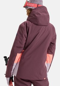 Purple ski jacket with a hood, featuring coral and light gray panels. Smooth fabric texture, designed for winter activity.