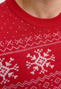 Suéter de punto rojo con un patrón de copos de nieve blancos, cuello acanalado y tejido texturizado con puntos variados.