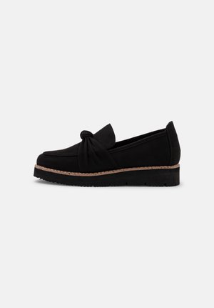 Chaussure noire en daim à enfiler avec un accent noué, dotée d'un panneau latéral texturé et d'une semelle tissée contrastante. Profil bas avec bout rond.