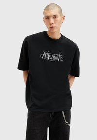 Sort bomulds t-shirt med et dristigt metallisk grafisk logo på forsiden. Korte ærmer, klassisk rund hals, afslappet pasform.