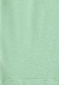 Tissu vert clair avec une texture fine en maille et un ourlet doublement surpiqué soigné le long du bord inférieur.
