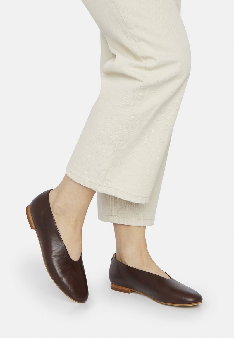 Scarpe in pelle marrone con punta affusolata e tacco basso. Il design presenta un'apertura a V e una superficie liscia.