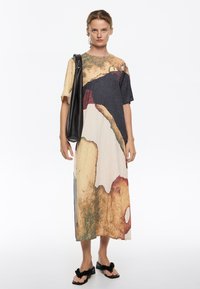 Vestido de manga corta con un patrón abstracto multicolor en beige, negro y verde; presenta una silueta holgada y una línea de dobladillo a la altura de la rodilla.
