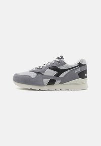 Sneaker in suede grigio e mesh con accento nero. Presenta un colletto imbottito, chiusura con lacci e suola testurizzata. Numero modello N.92.
