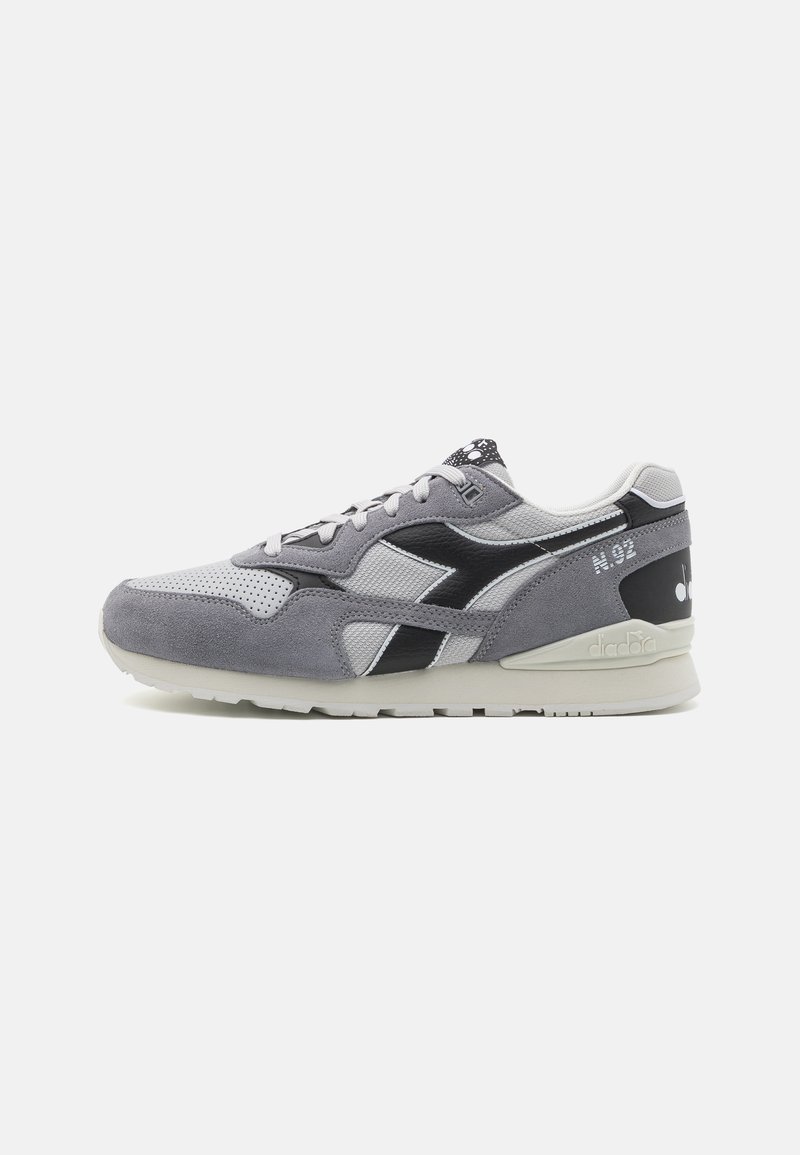 Sneaker in suede grigio e mesh con accento nero. Presenta un colletto imbottito, chiusura con lacci e suola testurizzata. Numero modello N.92.