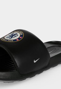 Μαύρο σανδάλι με λουρί με το λογότυπο της Chelsea Football Club και μικρό λευκό σήμα Nike στο πλάι.
