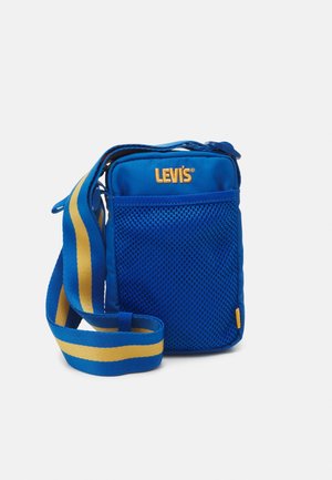Sac bandoulière Levi's bleu avec poche avant en mesh et sangle d'épaule réglable rayée bleu et jaune.