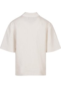 Majica s kratkimi rokavi v svetlo bež barvi iz zračnega lana. Ima klasičen ovratnik, sproščen kroj in minimalističen dizajn brez vidnih zapiral.