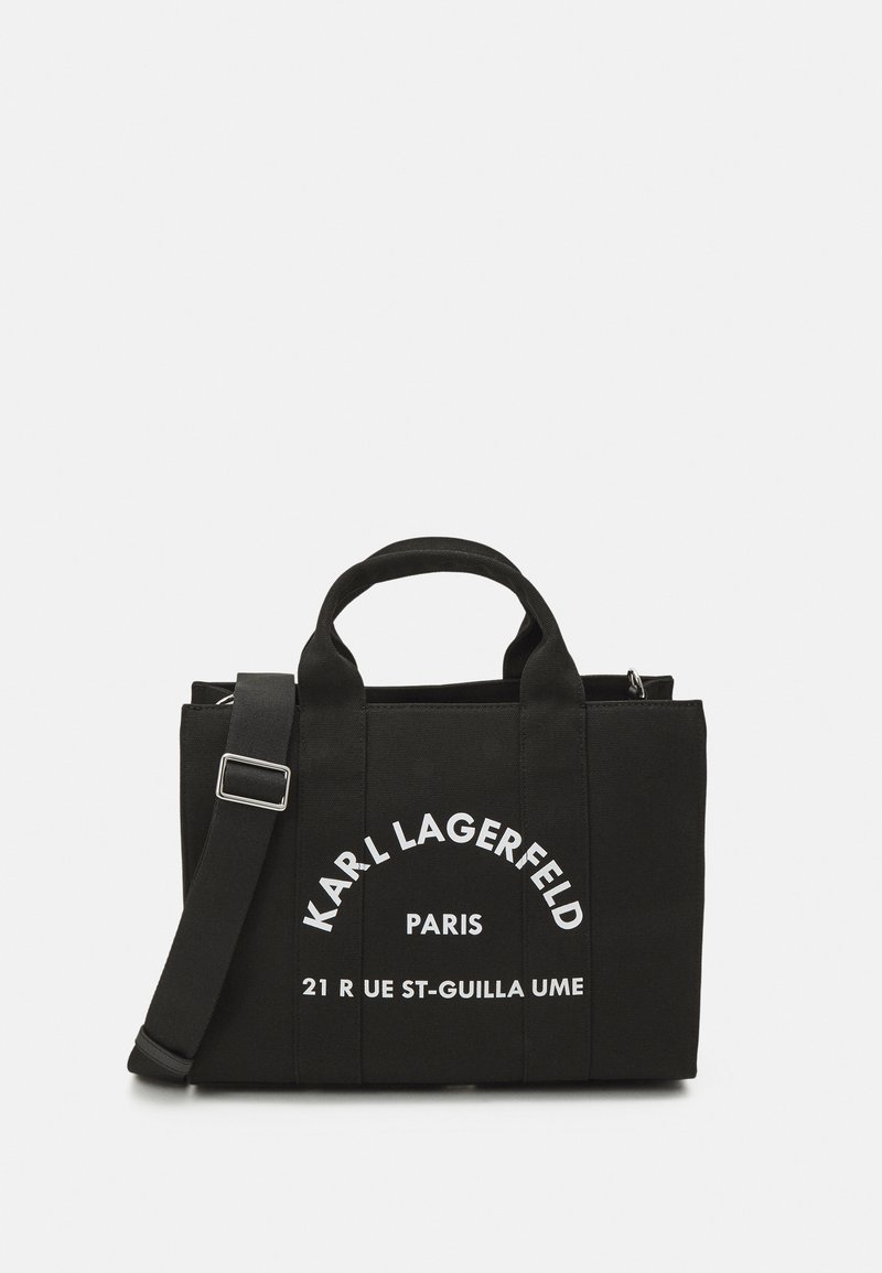 Czarna torba na ramię z podwójnymi uchwytami, regulowanym paskiem na ramię oraz białym napisem "KARL LAGERFELD PARIS" i adresem.