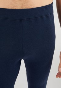 Navy blue fitted leggings made from ribbed knit fabric, featuring a soft waistband and a smooth texture, highlighting a sleek design.