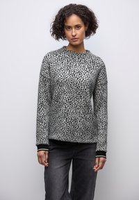 Šedý svetr s černými leopardími skvrnami, kulatý výstřih, žebrované manžety a pas. V kombinaci s tmavými džíny. Měkká, strukturovaná tkanina.
