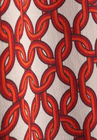 Sammankopplad röd och orange kedjemönster på texturerad beige tygbakgrund med detaljrik skuggning och överlappande länkar.