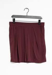 Gonna plissettata borgogna con elastico in vita, dotata di due tasche laterali e un tessuto morbido e testurizzato. Appesa a una gruccia nera.