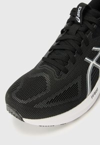 Black running shoe featuring a textured mesh upper with silver accents and laces, a white midsole, and a rubber sole with tread pattern.