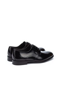 Zapatos de vestir de cuero negro con un acabado suave y brillante, puntera redonda y diseño con cordones. Presentan un sutil pespunte y una suela baja y plana.