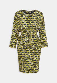 Robe longue aux genoux à manches longues avec un motif géométrique jaune, noir, blanc et marron, avec un col rond et une ceinture nouée à la taille.