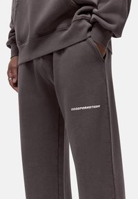 Gray sweatpants made of soft fabric with a relaxed fit, featuring a side pocket and white text "GOODFORNOTHING" on the thigh.
