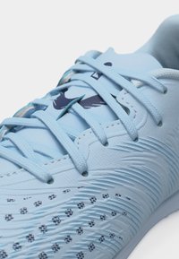 Chaussure de sport Nike bleu clair avec lacets, surface texturée et logo Swoosh bleu foncé sur la languette et le côté.