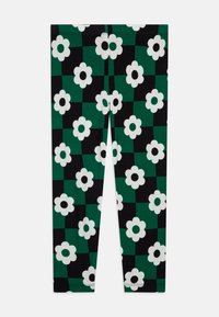 Leggings con un patrón a cuadros en verde y negro, adornados con grandes flores blancas. Están confeccionados con una tela elástica de textura suave.
