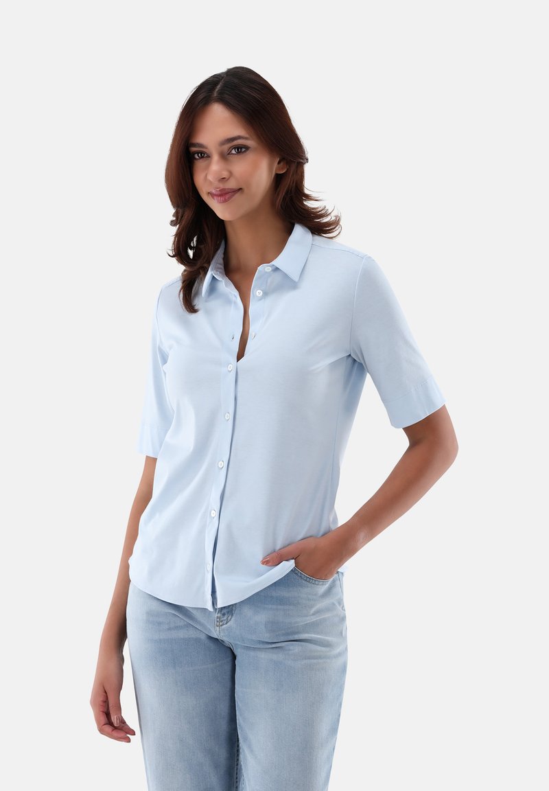 Light blue short-sleeve shirt with a button-down front, collar, and soft fabric. Paired with light blue denim pants.