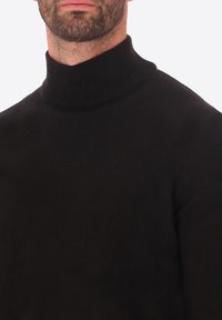 Maglione a collo alto di colore nero realizzato in materiale knit morbido, con un design aderente e colletto a coste. La texture appare liscia con motivi sottili.