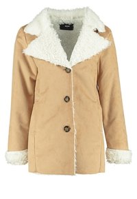 Tann faux mockajacka med vit pälskrage, fem svarta knappar framtill och vita pälskanter. Slät textur med synliga sömmar.