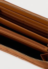 Καφέ δερμάτινο πορτοφόλι ανοιχτό που δείχνει πολλές θήκες καρτών και ένα κεντρικό φερμουάρ με χρυσούς φερμουάρ σε λευκό φόντο.