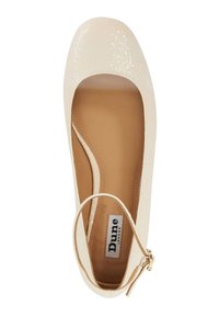 Chaussure plate de couleur crème avec une finition texturée brillante, bout rond et une bride réglable à la cheville avec un détail de boucle dorée.