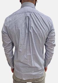 Camicia a righe bluo e bianco con bottoni, caratterizzata da una piega sul retro e maniche lunghe, realizzata in un tessuto morbido con una leggera texture.