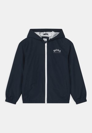Granatowa kurtka z kapturem, z pełnym białym zamkiem z przodu i logo „BOSS HUGO BOSS” na lewej piersi, elastycznymi mankietami oraz siateczkową podszewką wewnątrz kaptura.