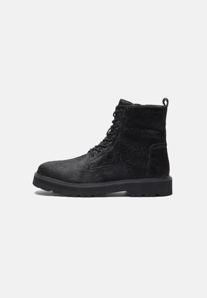 Black ankle boots with a textured upper, featuring lace-up front, sturdy rubber sole, and a pull tab at the back for easy wear.
