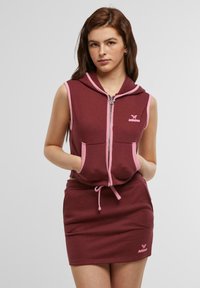 Vinrød ermeløs hettekjole med rosa detaljer, med frontglidelås, to frontlommer og elastisk midje med snøring.