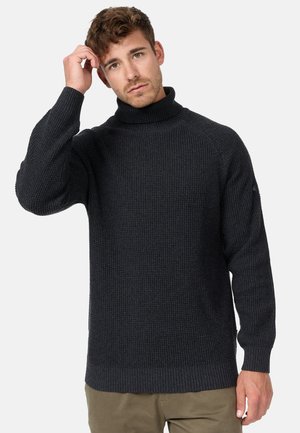 Suéter de punto gris oscuro con cuello alto, patrón texturizado, mangas largas y puños y dobladillo acanalados. El modelo lleva pantalones caqui.