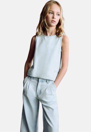 Lichtblauw denim mouwloze top met een ronde halslijn, gecombineerd met hooggetailleerde, wijde lichtblauwe broek met zijzakken.