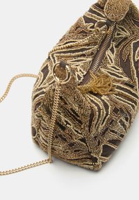 Rjava torbica z biseri in z zlato verižico. Ponaša se z izpopolnjenim vzorcem biserov različnih tekstur in oblik, z zadrgo za zapiranje ter okrasnimi dodatki.